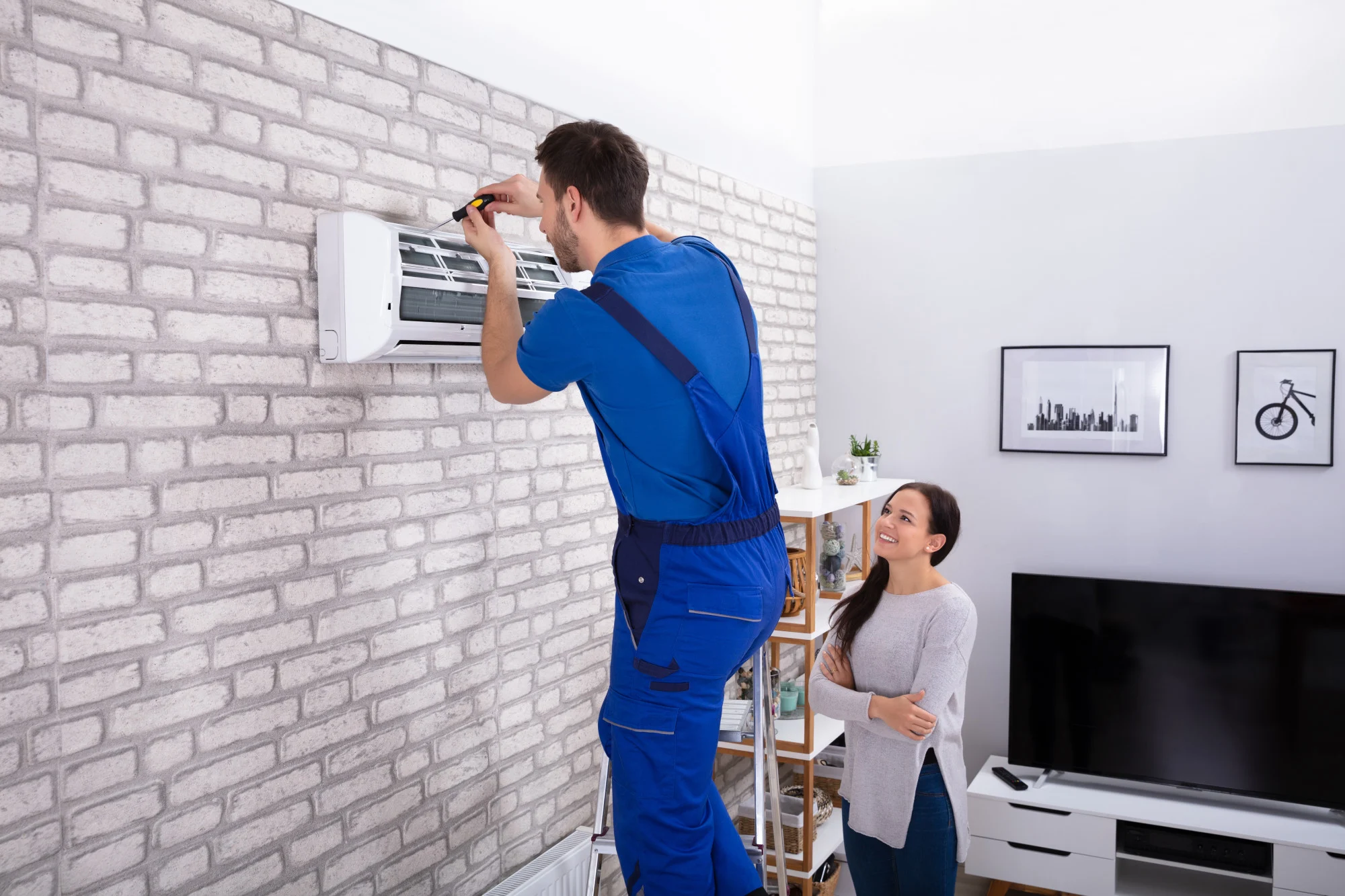 tech repairing ac unit for woman in home